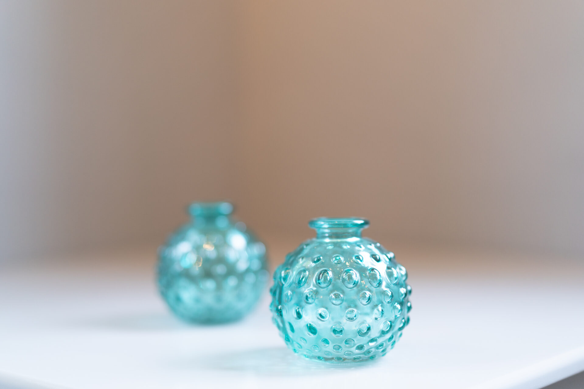Two small blue glass vases sitting on a table.