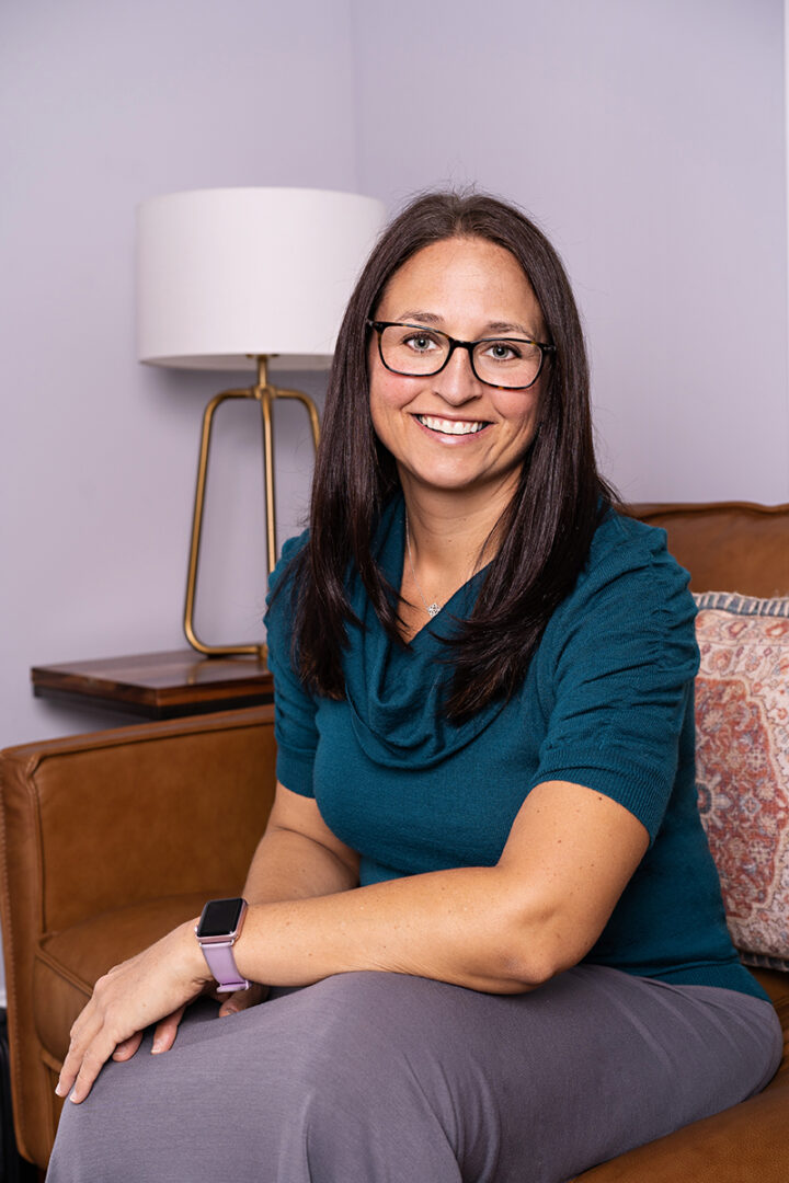 A woman sitting on top of a couch wearing glasses.